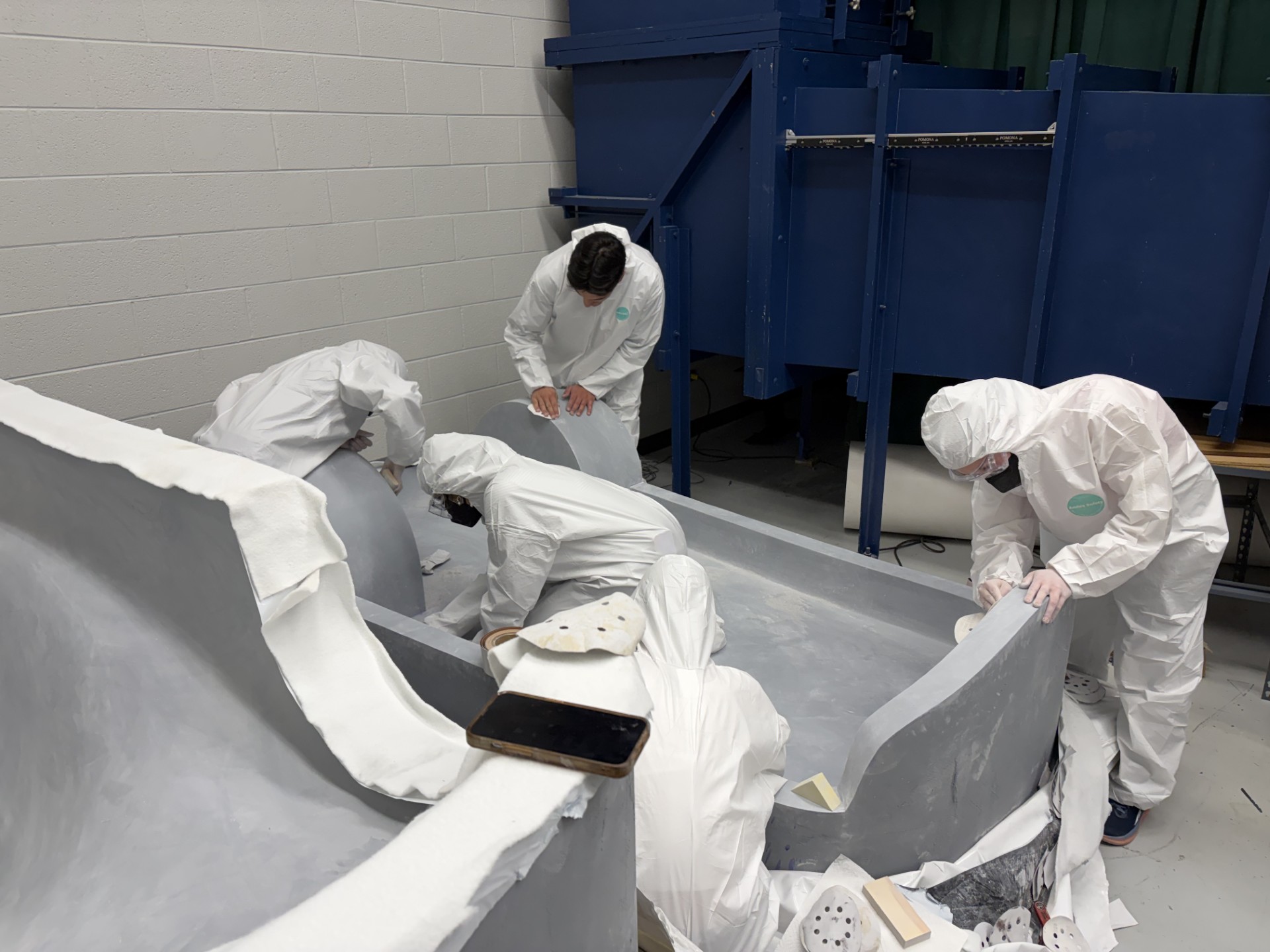 Team members in protective suits hand-fairing the body molds